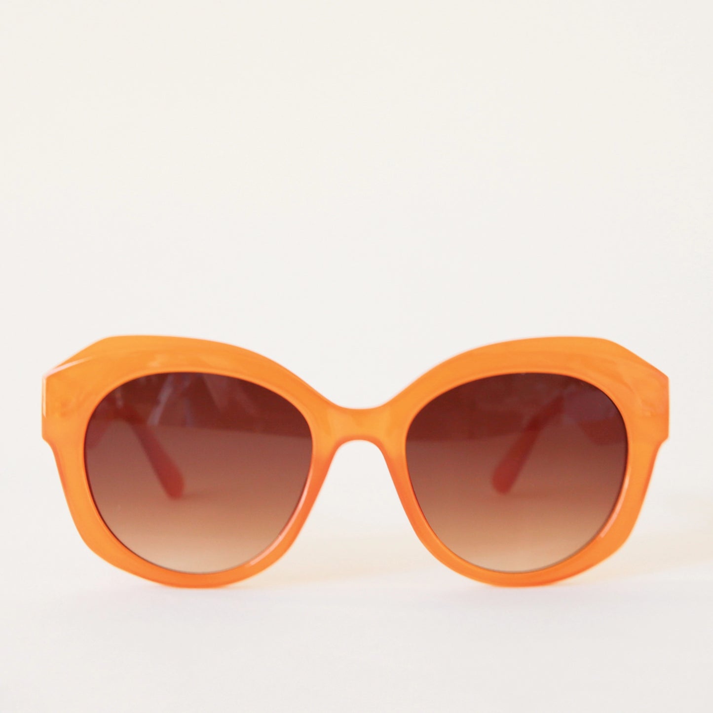 Chunky round orange sunglasses with a brown lens.