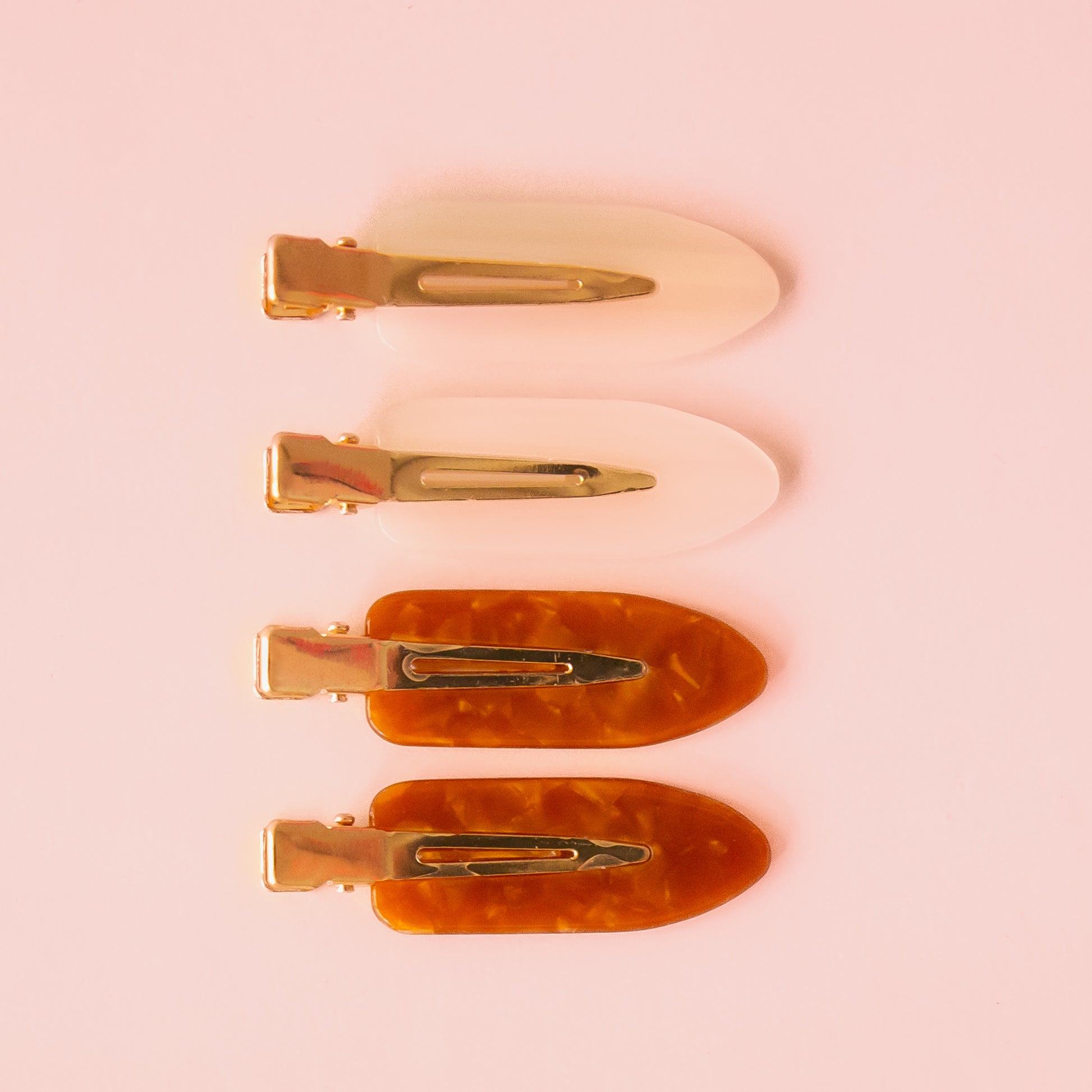 A set of four creaseless hair clips in a brownish shade and ivory tone. 