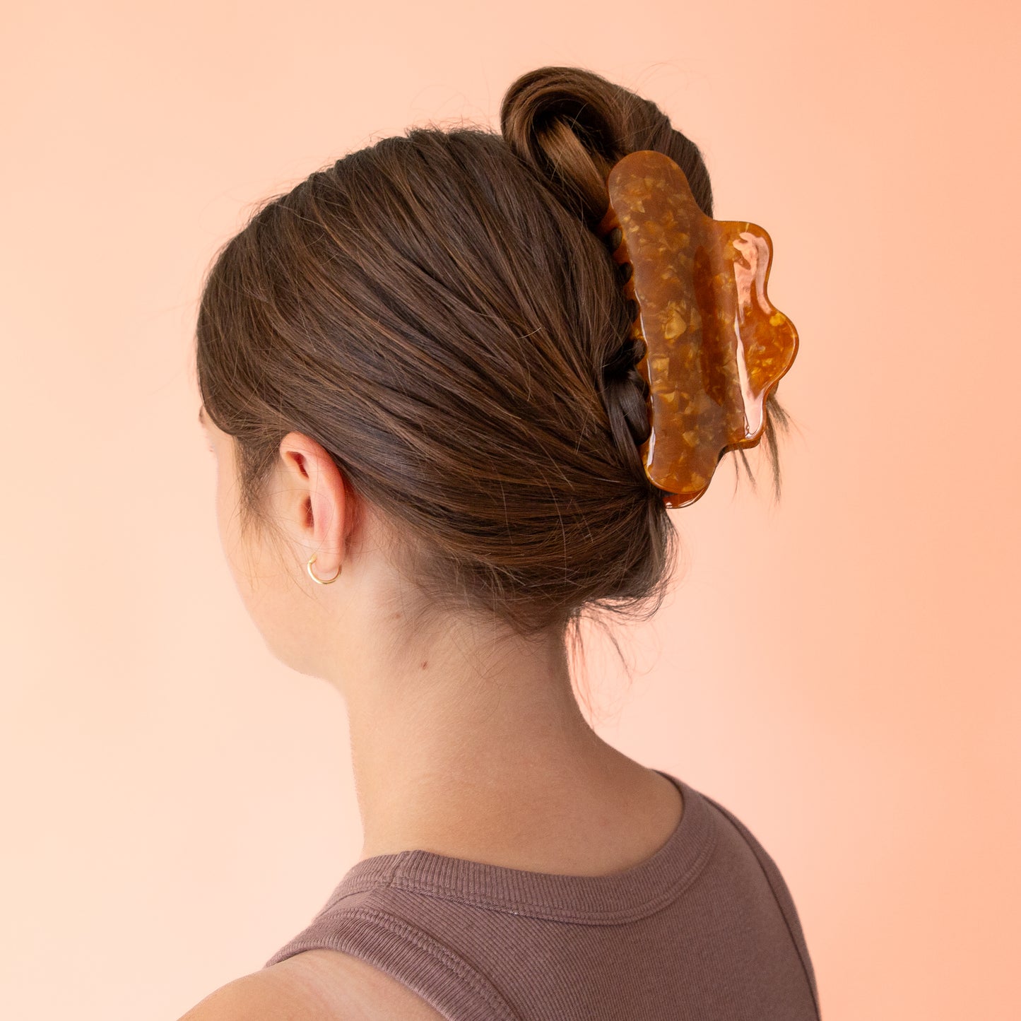 A brown acetate hair claw clip with a wavy rounded edge.