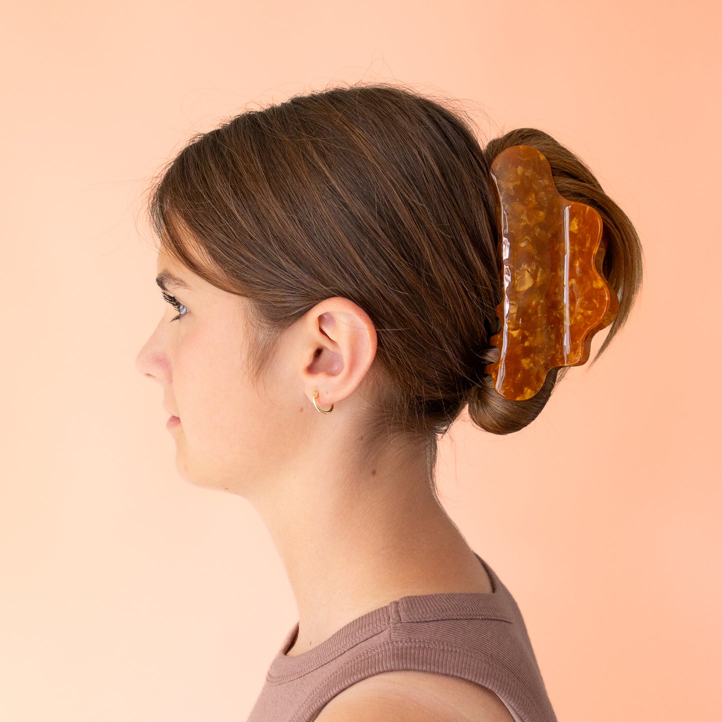 A brown acetate hair claw clip with a wavy rounded edge.