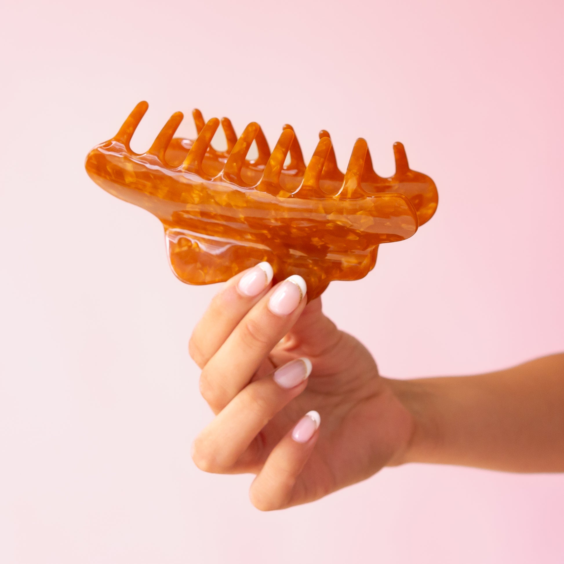 A brown acetate hair claw clip with a wavy rounded edge. 