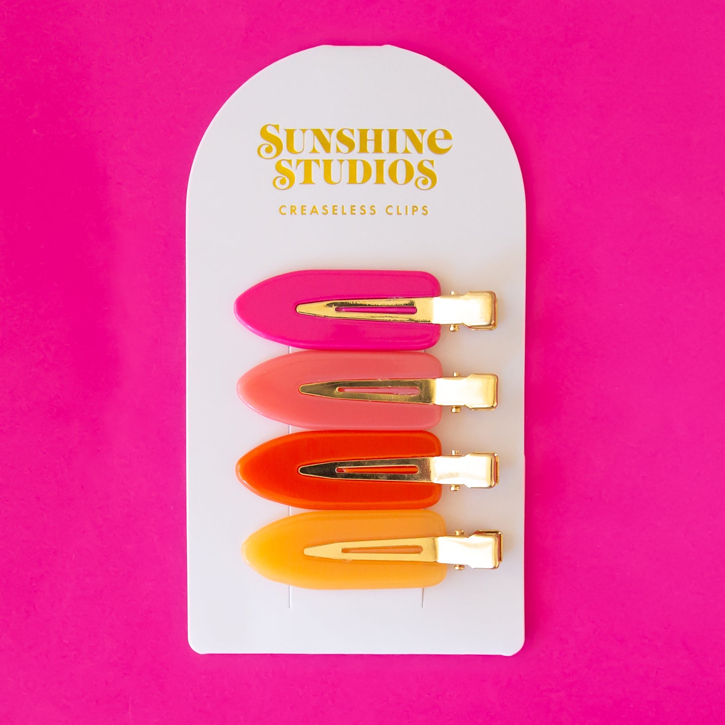 Four vibrant colored creaseless hair clips in orange, pink and yellow shades.