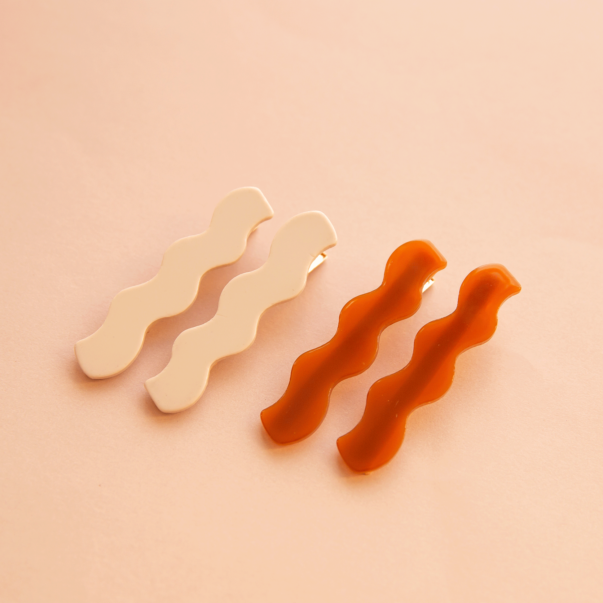 On a peach background is two pairs of wavy hair clips.