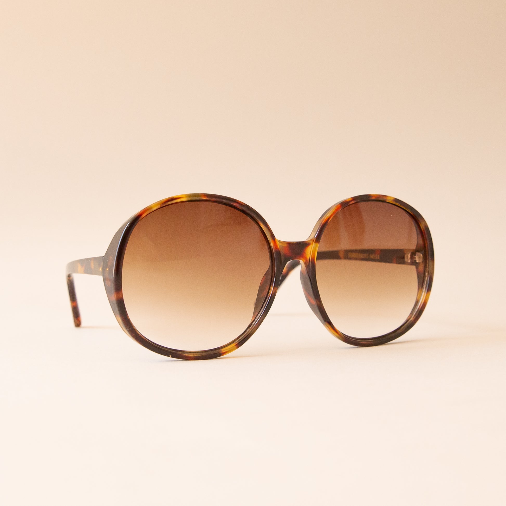 A tortoise brown pair of round oversized sunglasses with a light brown lens.