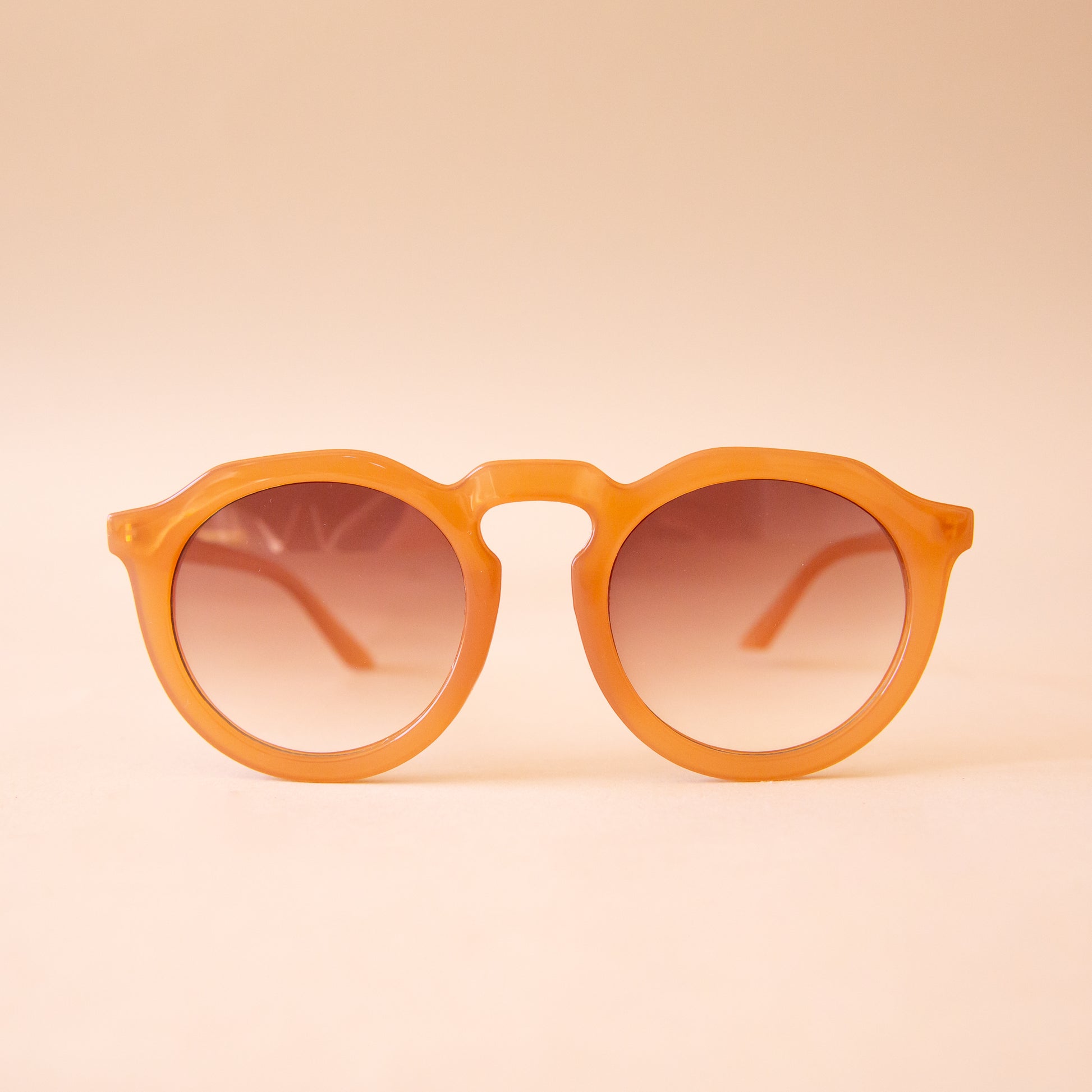 A warm brown pair of round sunglasses with a brown gradient lens. 