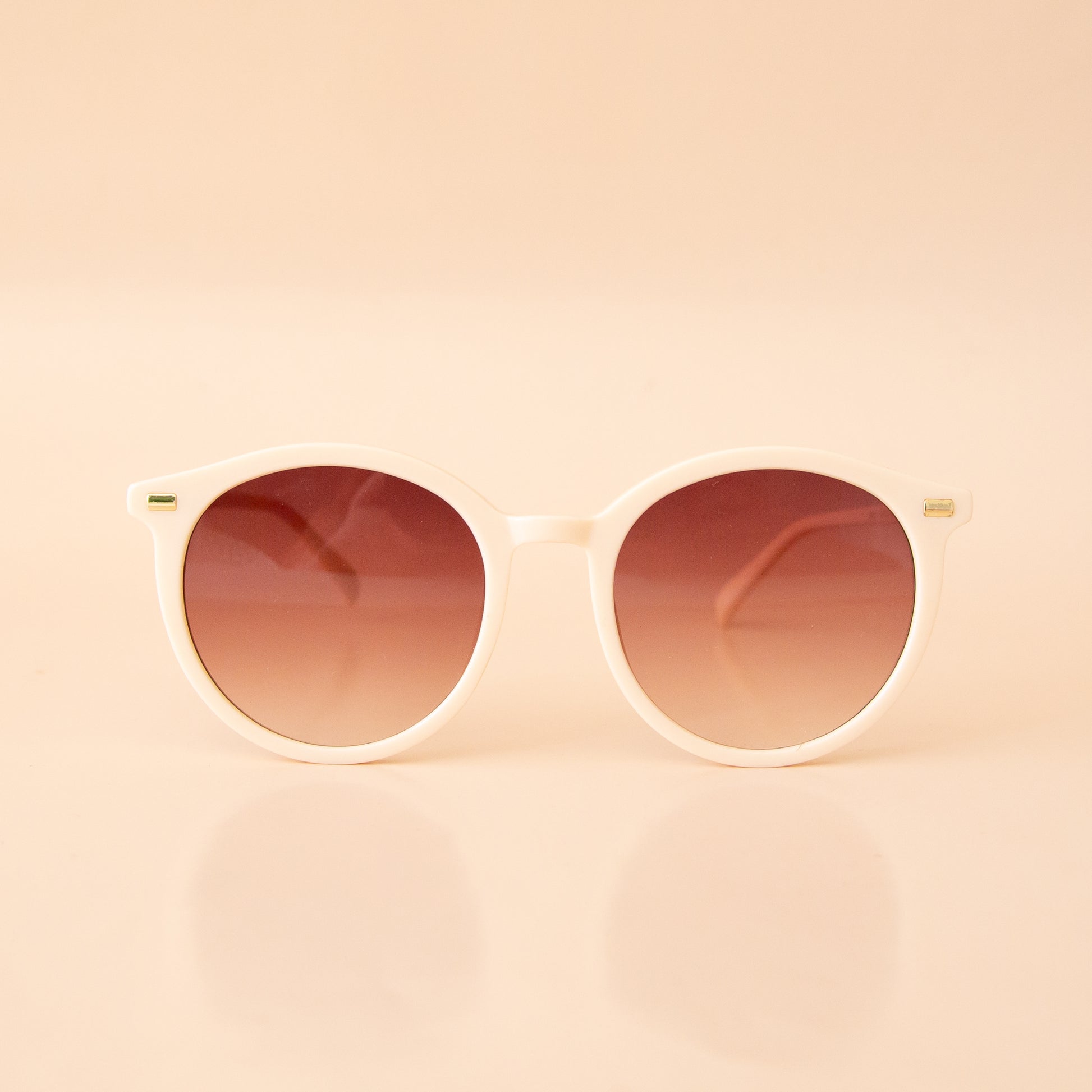 A white pair of rounded sunglasses with a brown lens.