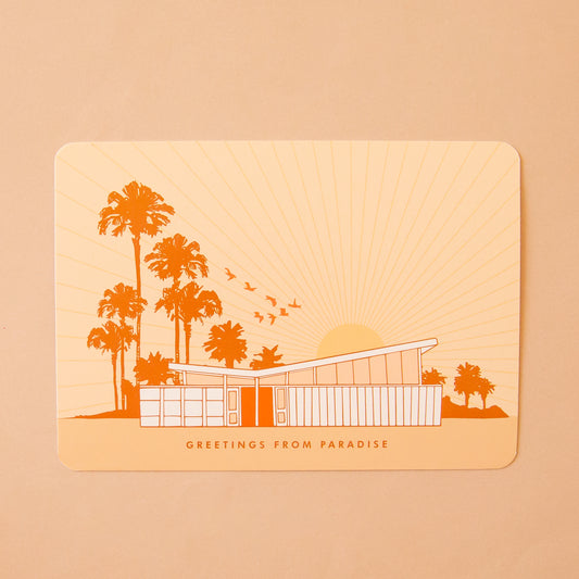 A yellow postcard with an orange palm tree and mid-century home design and text below that reads, "Greeting From Paradise". 