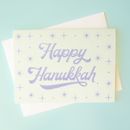 A light blue card with text that reads, "Happy Hanukkah".