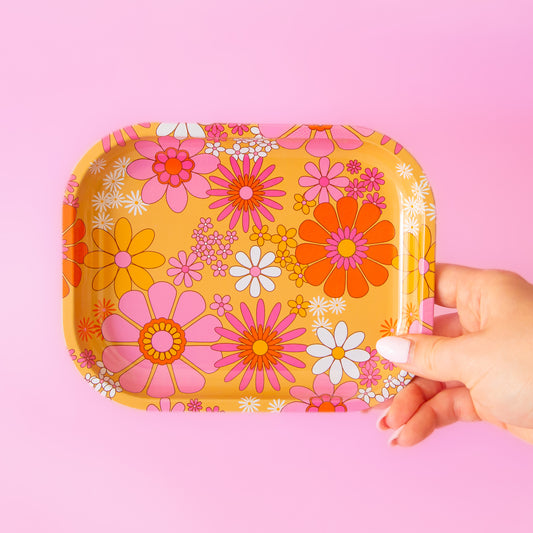 hand holding floral metal tray against a pink background