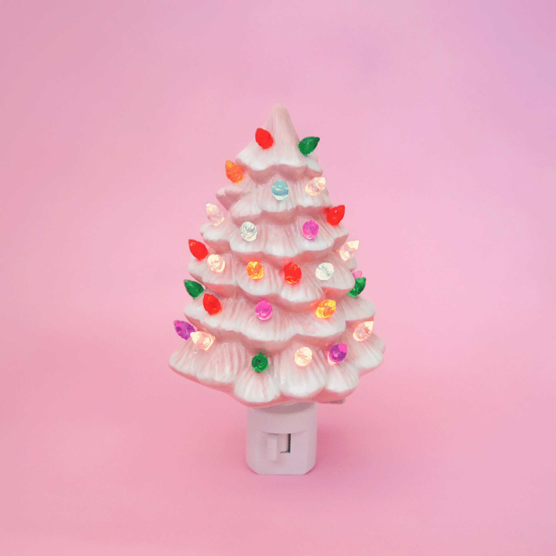 A ceramic christmas tree shaped night light.  The night light has multi colored lights all over it and the ceramic is pink.