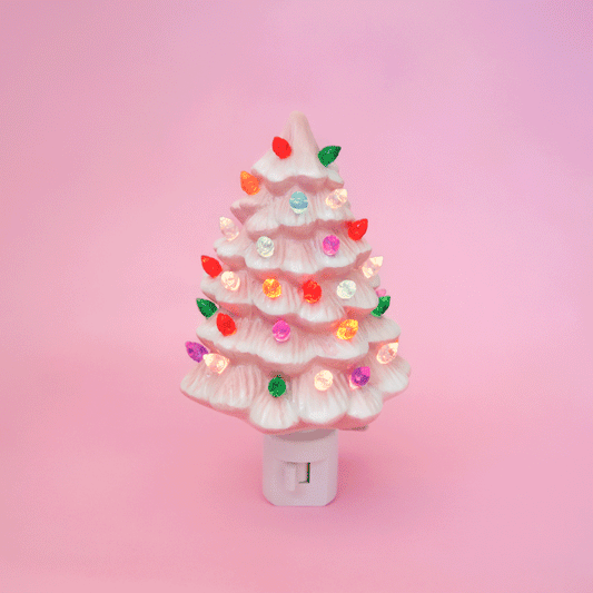 A ceramic christmas tree shaped night light.  The night light has multi colored lights all over it and the ceramic is pink.