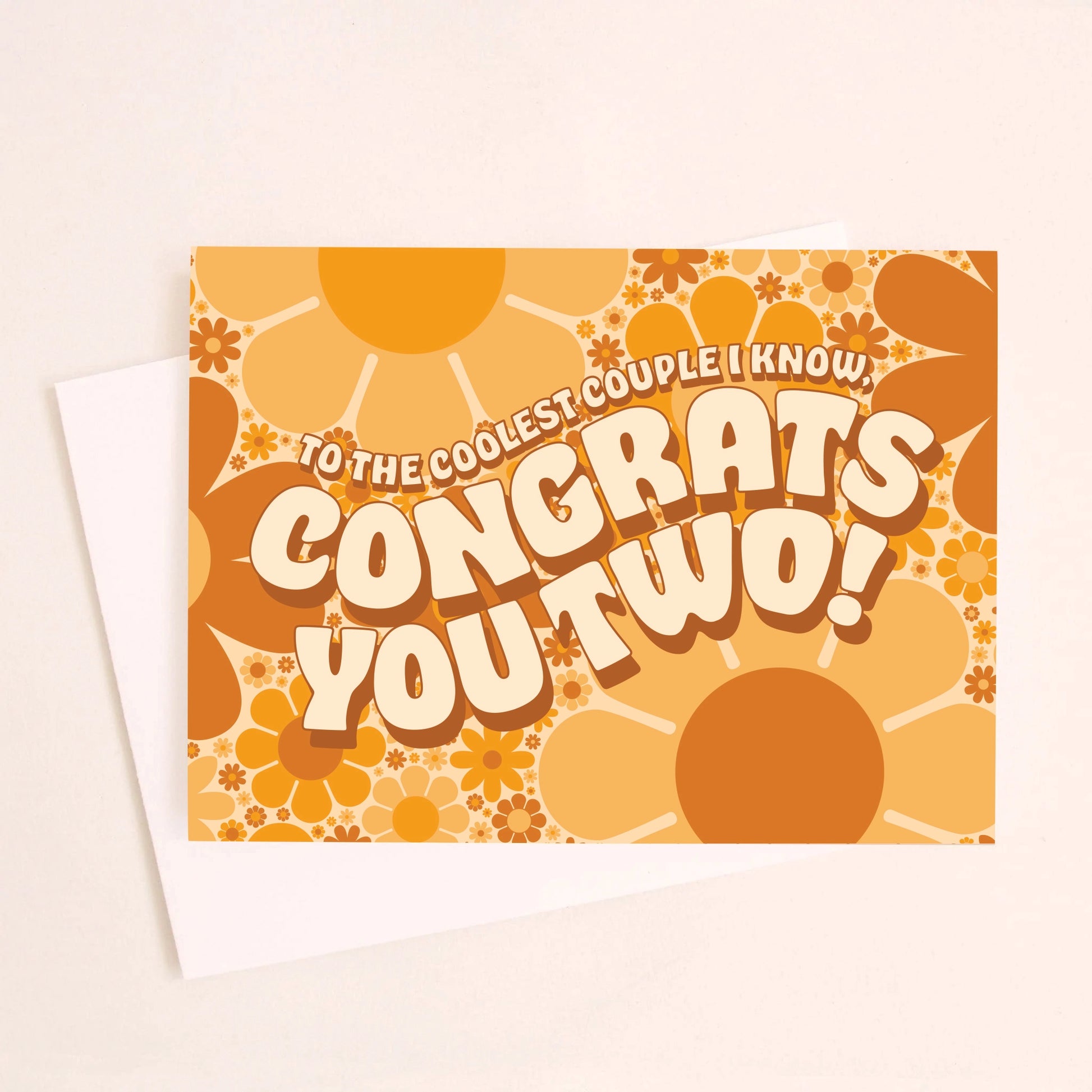 On an ivory background is a daisy print congratulations card with shades of orange and brown along with wavy text in the center that reads, "To The Coolest Couple I Know, Congrats You Two!". 