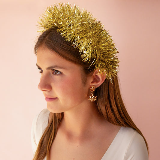 A gold tinsel headband sits on a young girls head.