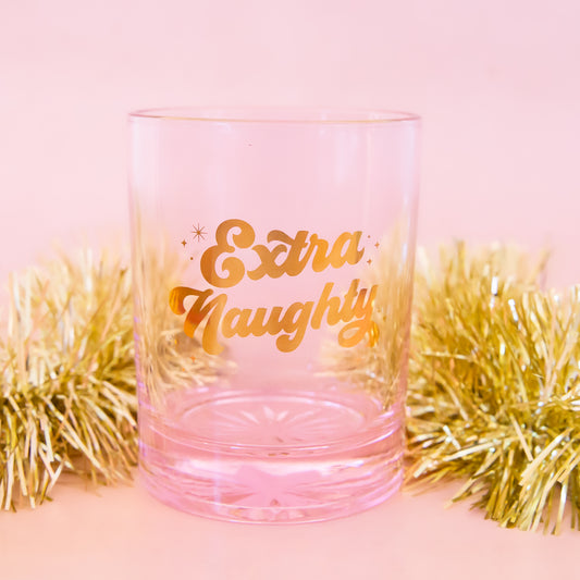 pink glass tumbler with gold script font that says "extra naughty"
