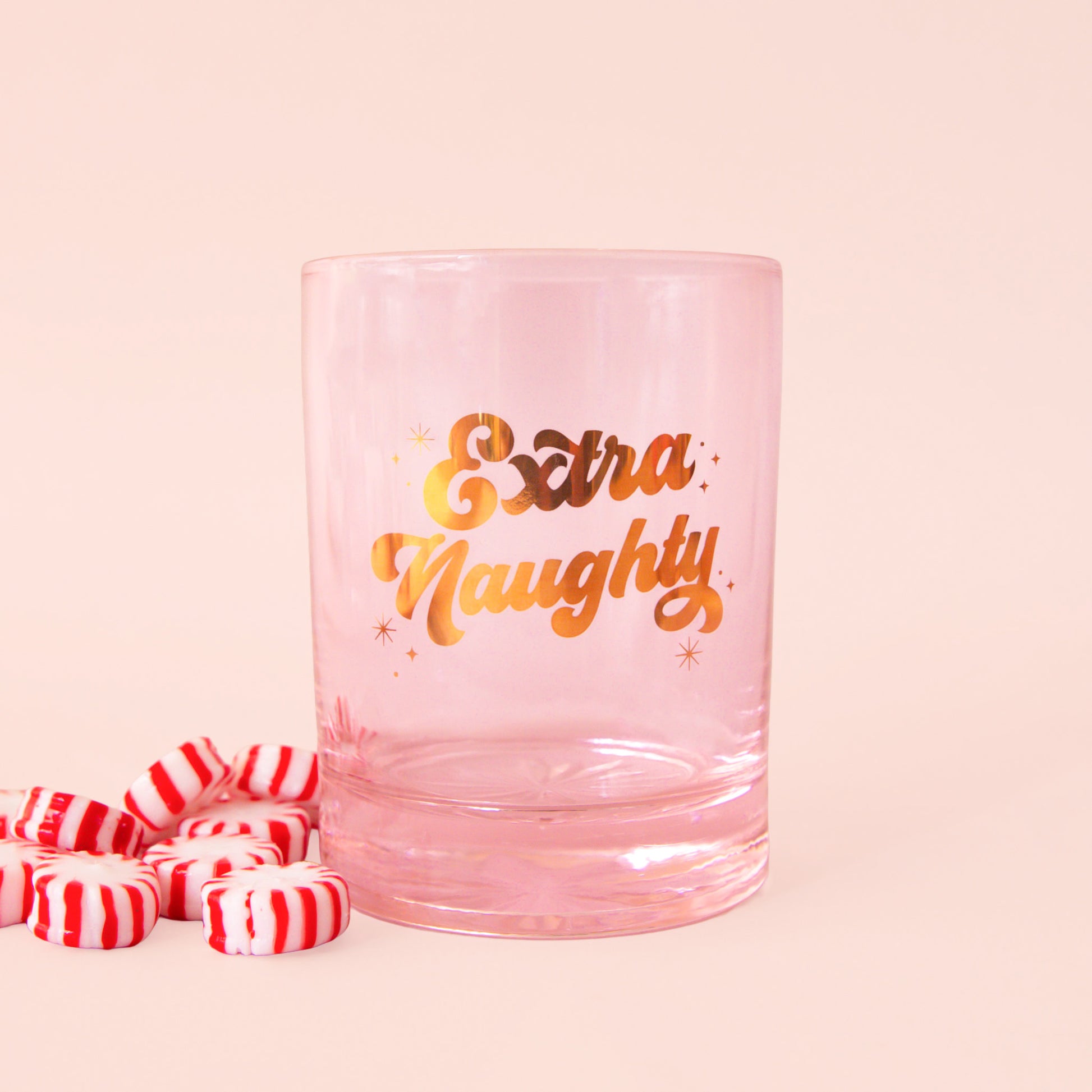pink glass tumbler with gold script font that says "extra naughty"