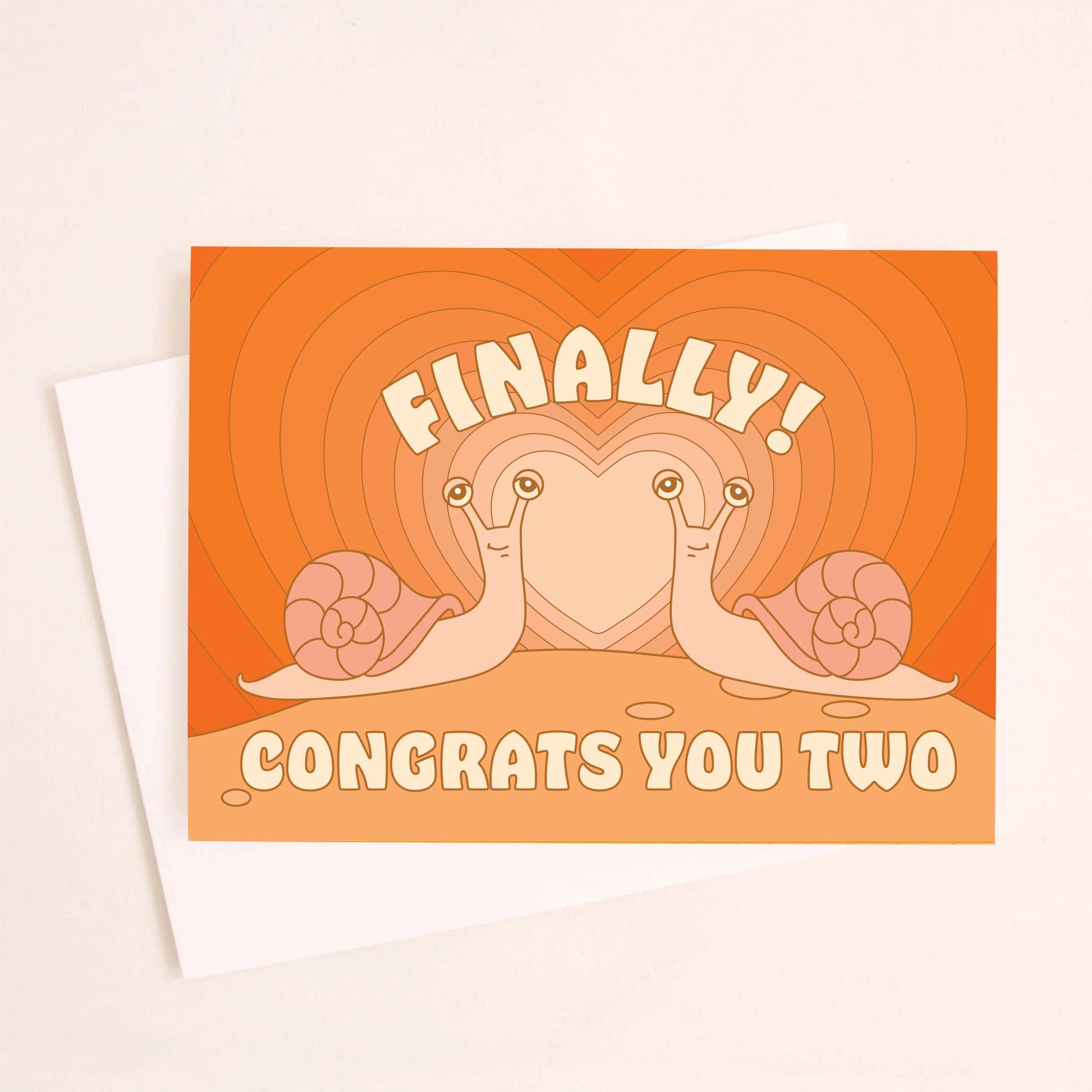 On an ivory background is a greeting card with an orange gradient heart card background with two snails coming towards one another and text above and below that reads, "Finally Congrats You Two". 