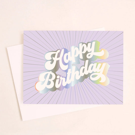 On an ivory background is a purple greeting card with white, holographic outlined text that reads, "Happy Birthday". 