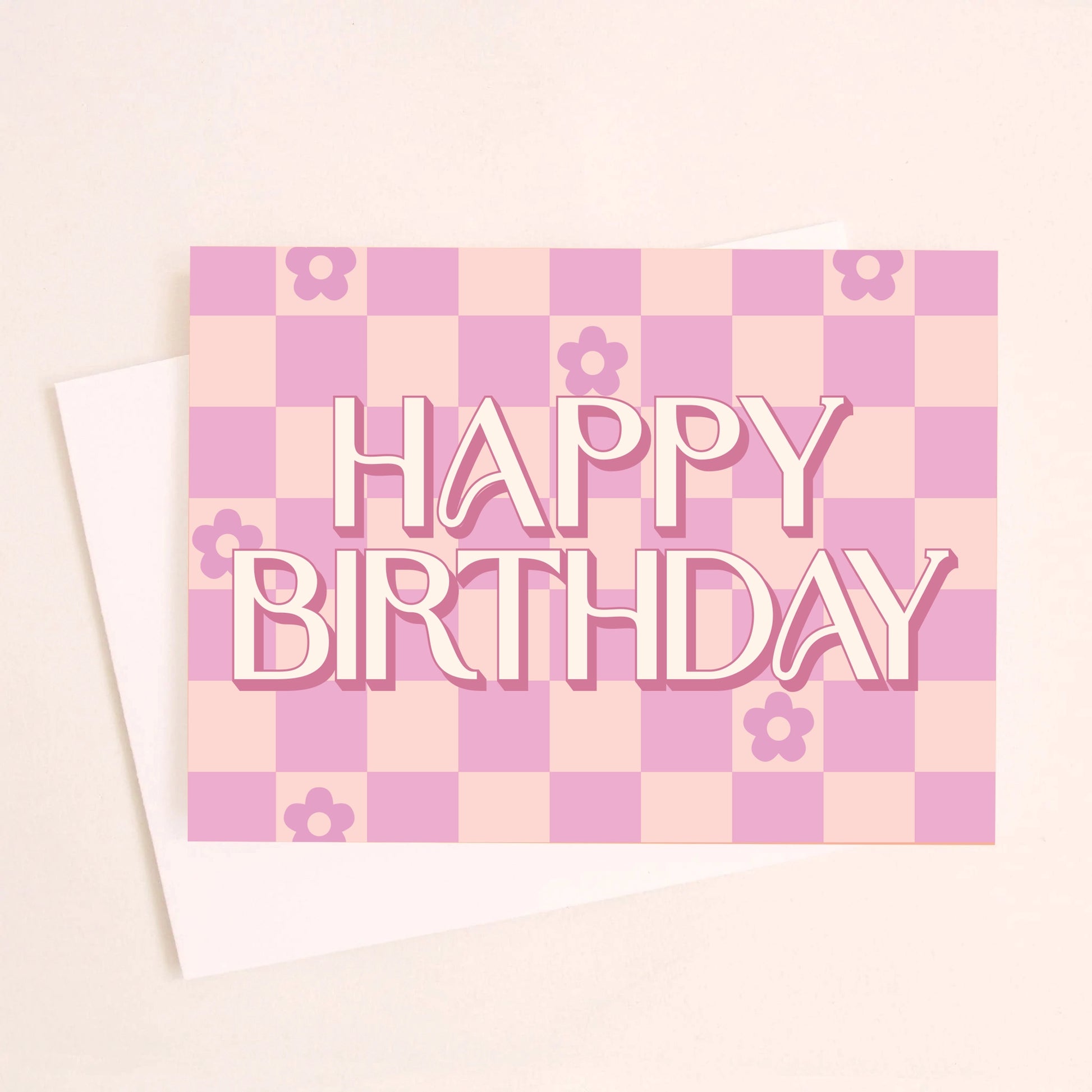 On a peachy background is a hot pink and light pink checkered greeting card with flowers in six of the checker squares along with text in the center that reads, "Happy Birthday". 