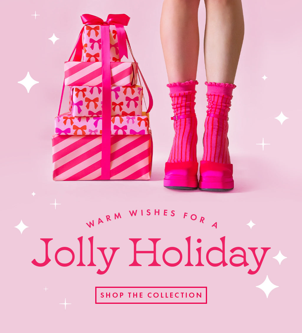 Pink shoes and socks stand on a pink background next to a pile of presents.  The text reads "Warm wishes for a jolly holiday"