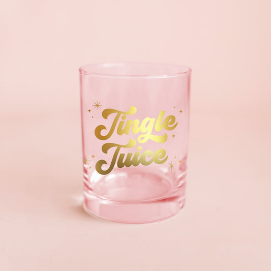 Glass cup with gold lettering is shown against a pink background