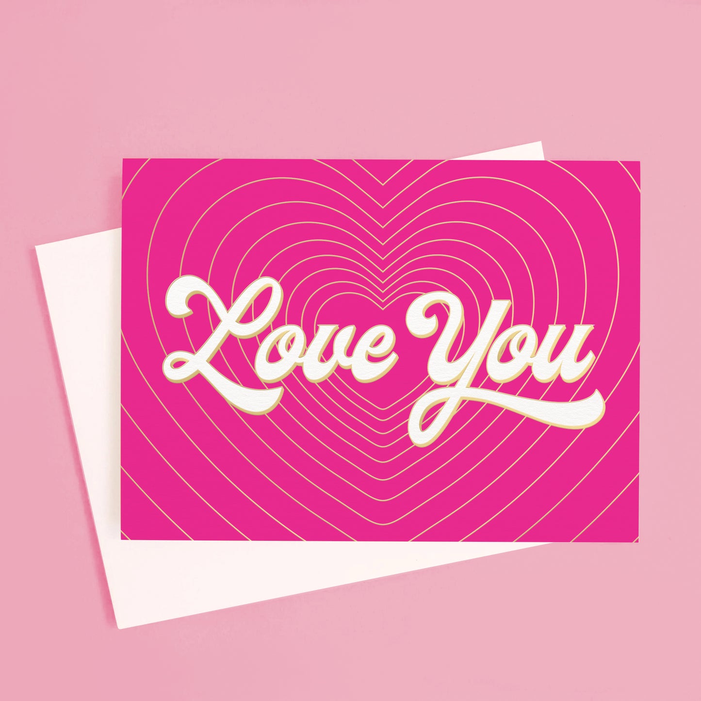 On a pink background is a hot pink card with gold heart shaped lines with ivory text in the center that reads, "Love You".