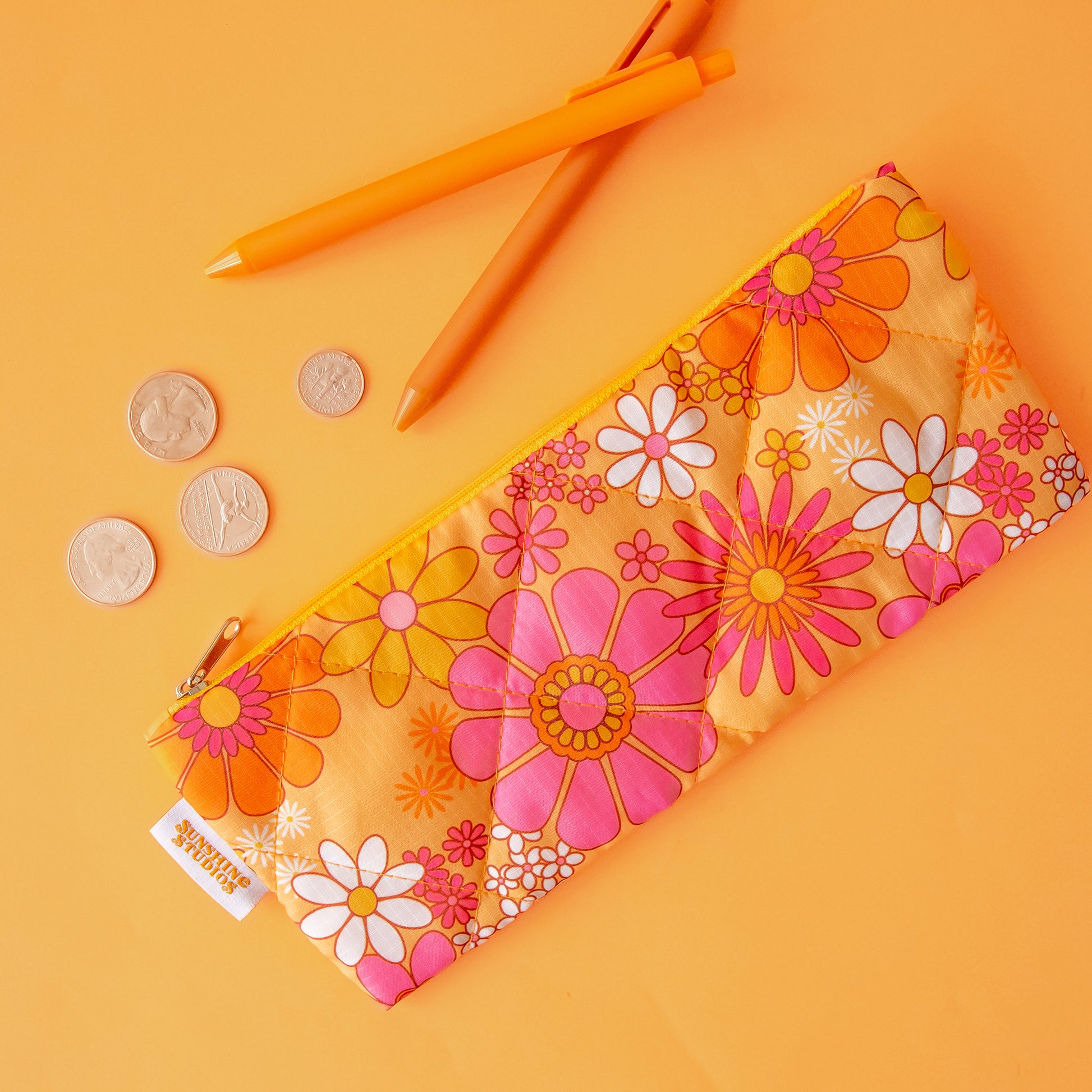 A floral print pencil pouch in orange, pink and ivory tones. 