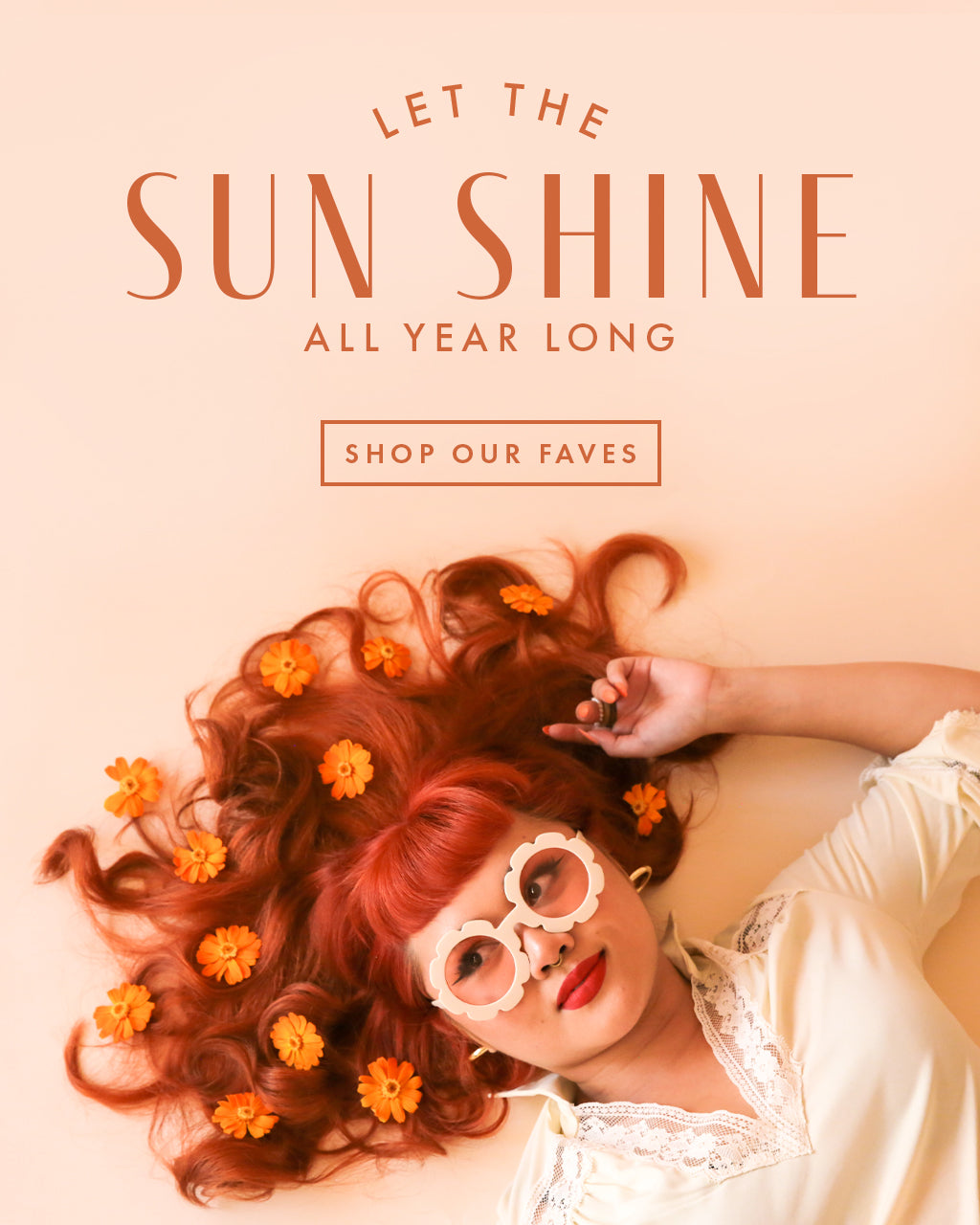 let the sun shine all year long. shop our faves. a woman with red hair lies on the flower with orange flowers in her hair while wearing a pair of white flower sunglasses