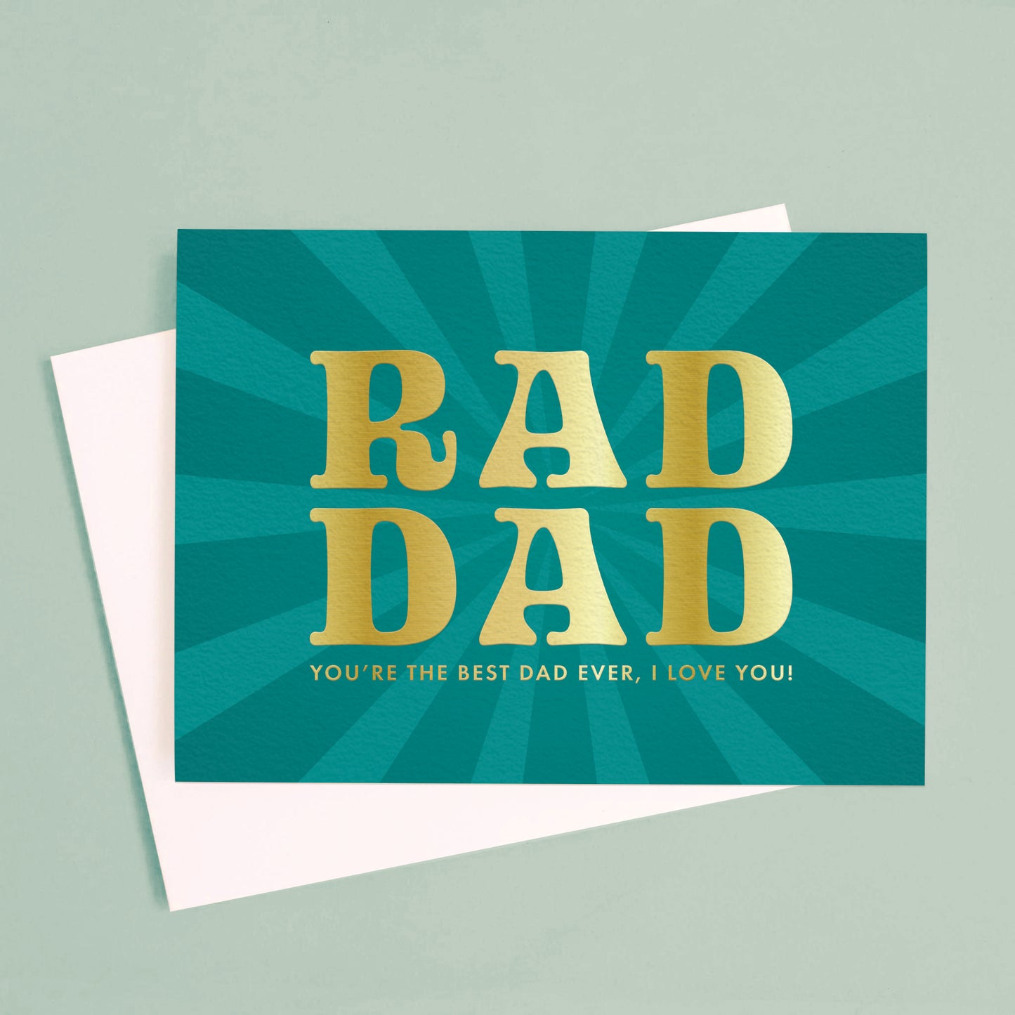 On a green background is a blue teal card with gold text that reads, "Rad Dad You're The Best Dad Ever, I Love You". 