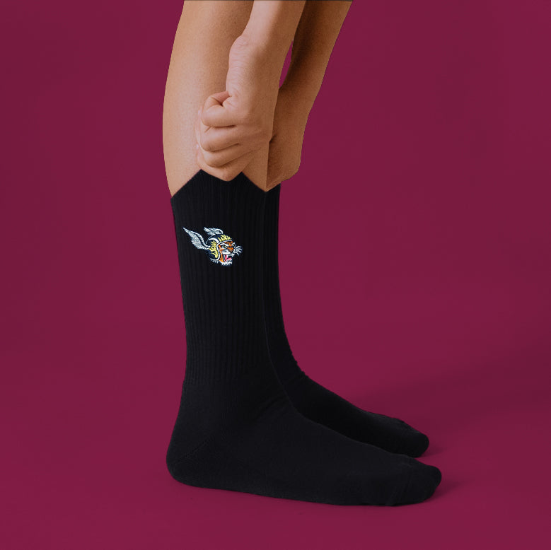 A black pair of crew socks with a tiger with a wing helmet graphic on the side. 