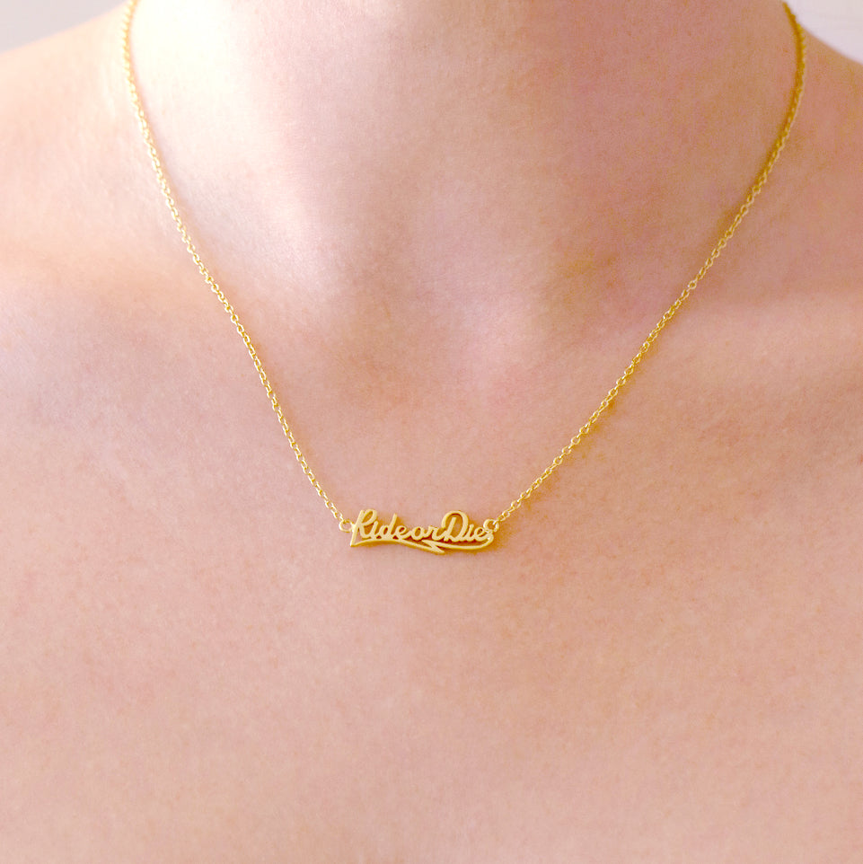 Gold necklace with 'Lifestyle' pendant on a person's neck