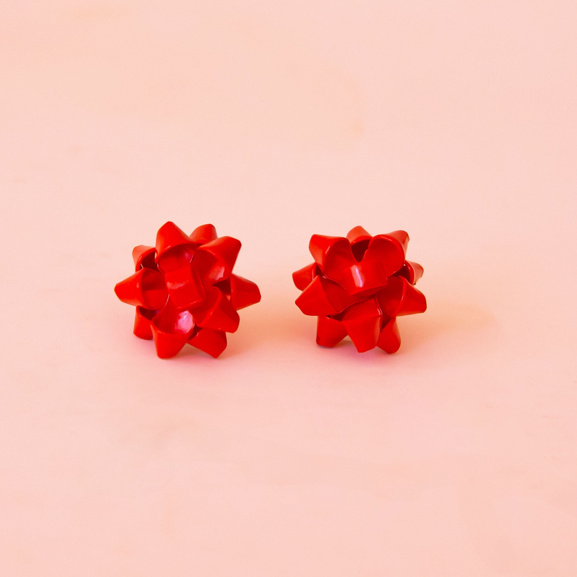 A red pair of bow shaped earrings. 