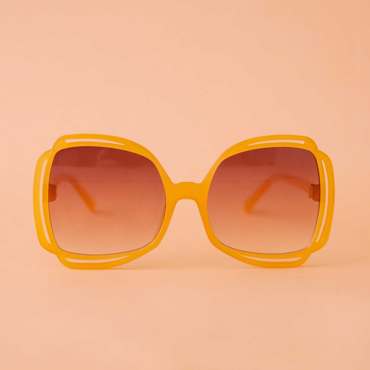 A pair of round sunglasses with yellow frames and a brown gradient lenses. 