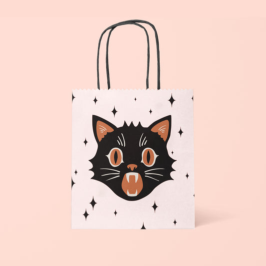 Light pink gift bag with a black and orange cat face and black stars. 