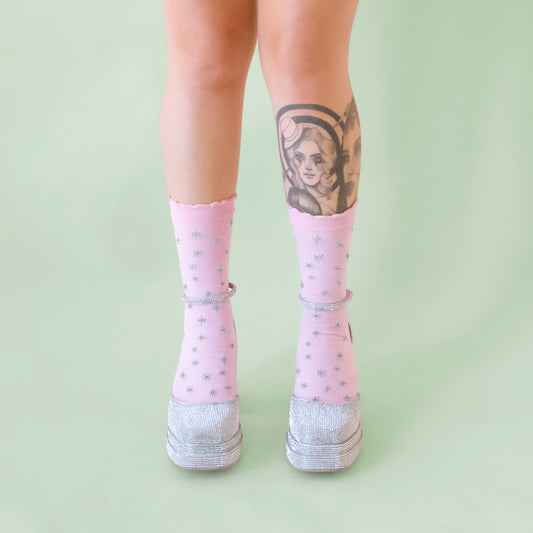 A pair of light pink socks with a silver star pattern. 