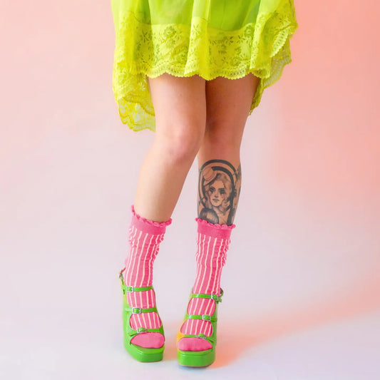 Model in lime green dress and shoes, with pink striped crew socks on.