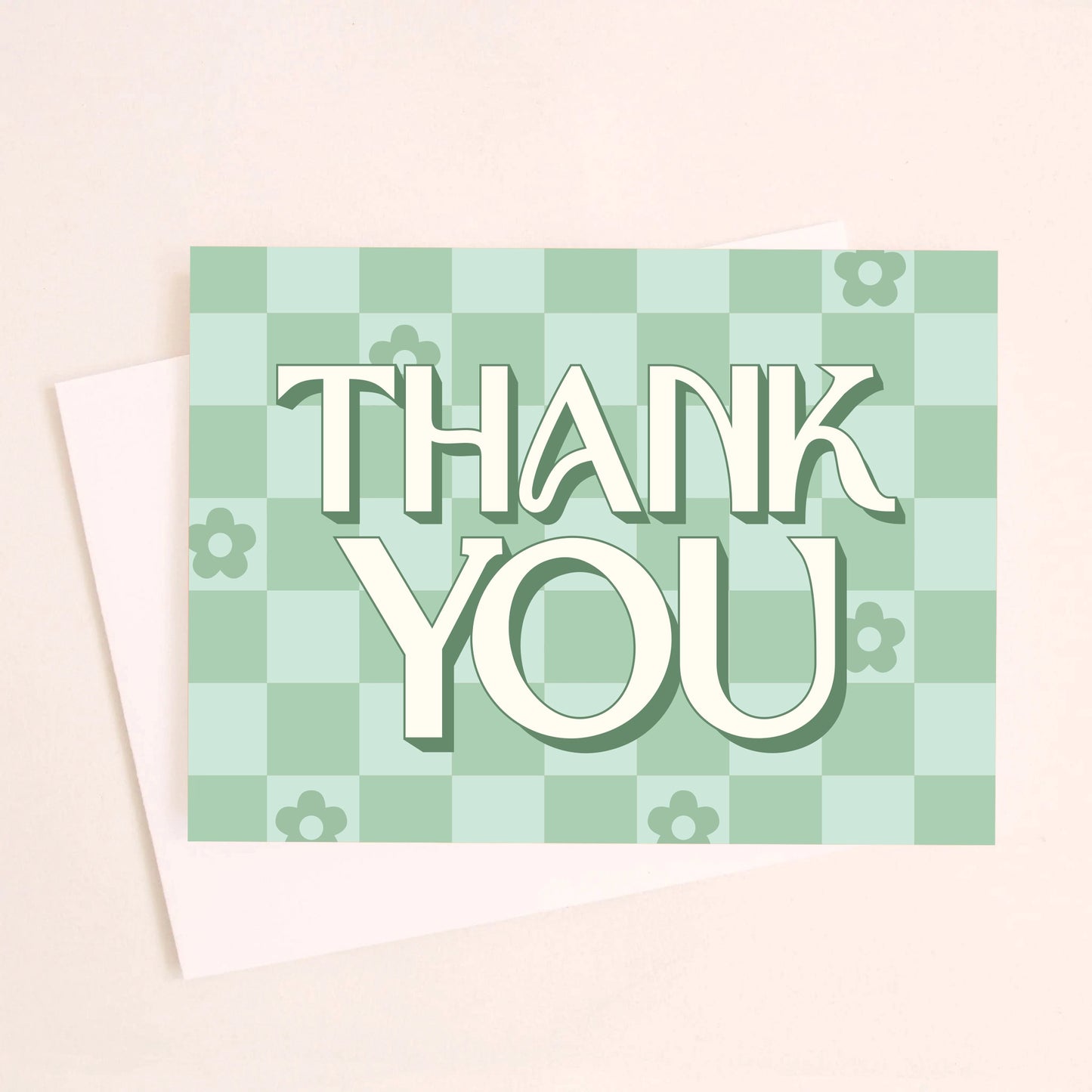 On a white background is a green checker print greeting card that reads, "Thank You" along with scattered daisies in some of the squares. 