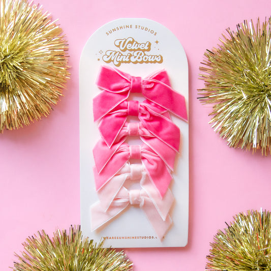 On a pink background is a set of velvet bows in three different shades of pink. 