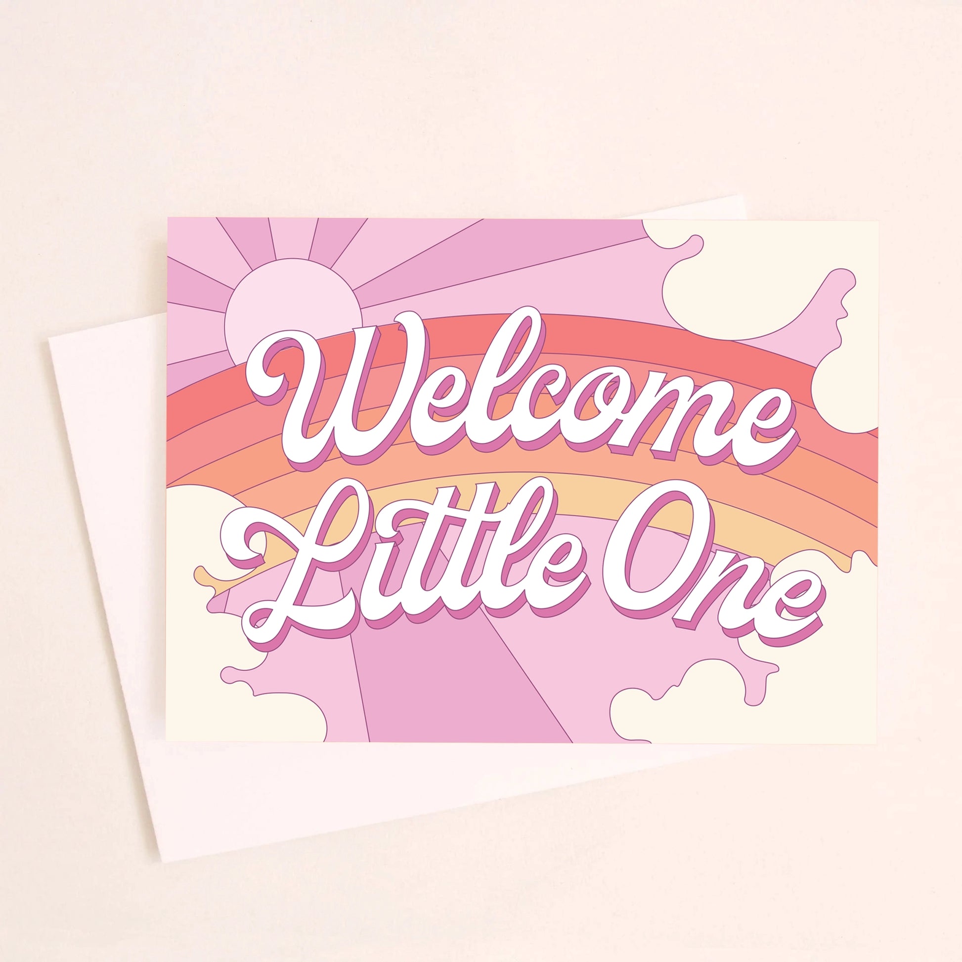 On a light pink background is a greeting card featuring a rainbow and sun graphic and white text in the center that reads, "Welcome Little One".