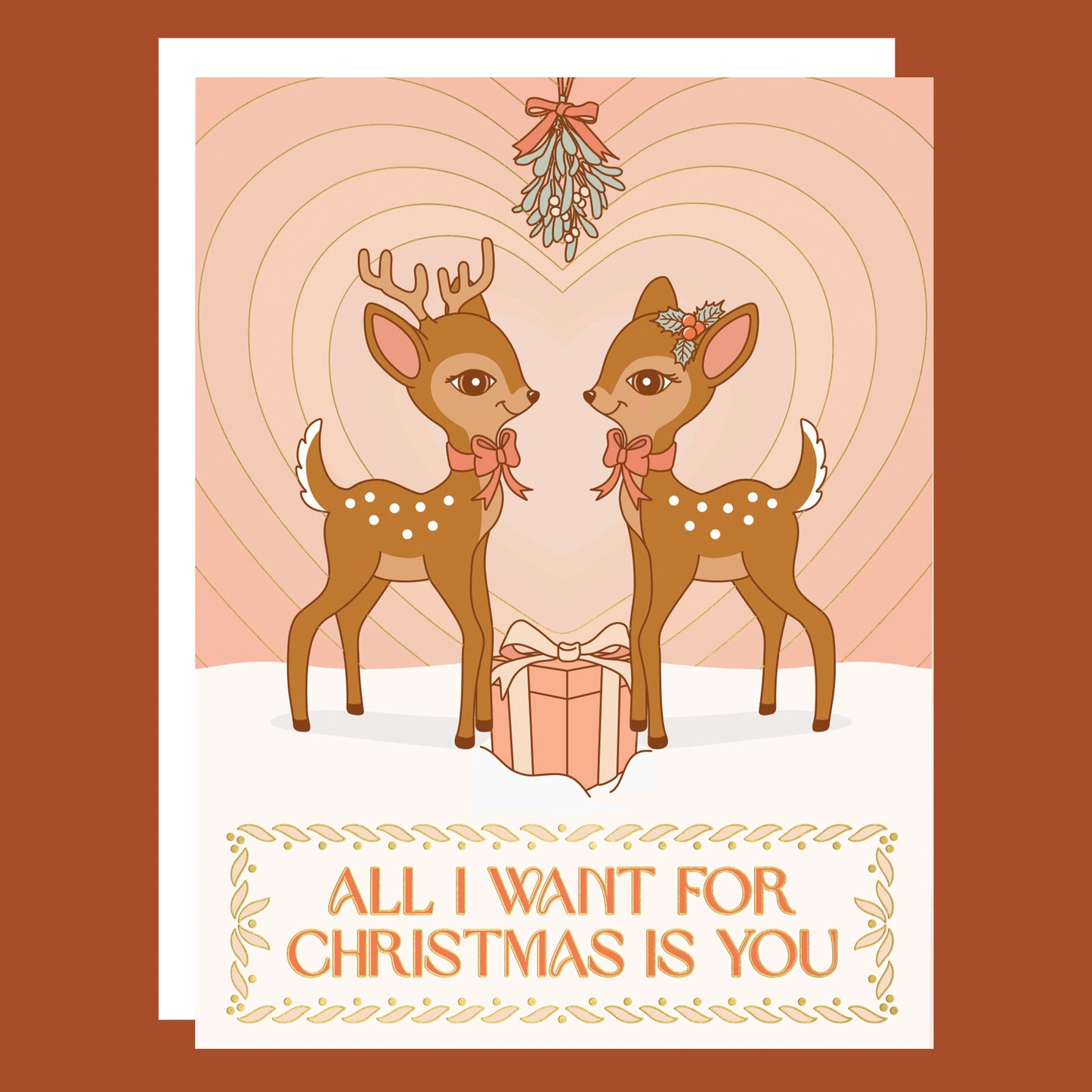 On a neutral background is a light pink card with two brown retro deer looking towards one another underneath mistletoe with a gradient heart in the background and text below the image that reads, "All I Want For Christmas Is You"