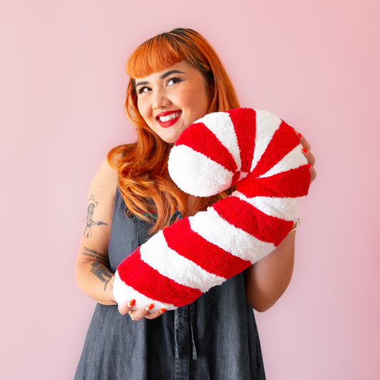 A red and white candy cane shaped pillow. 