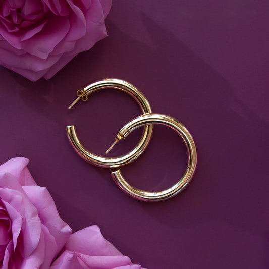 A pair of chunky gold hoop earrings with a straight post backing. 