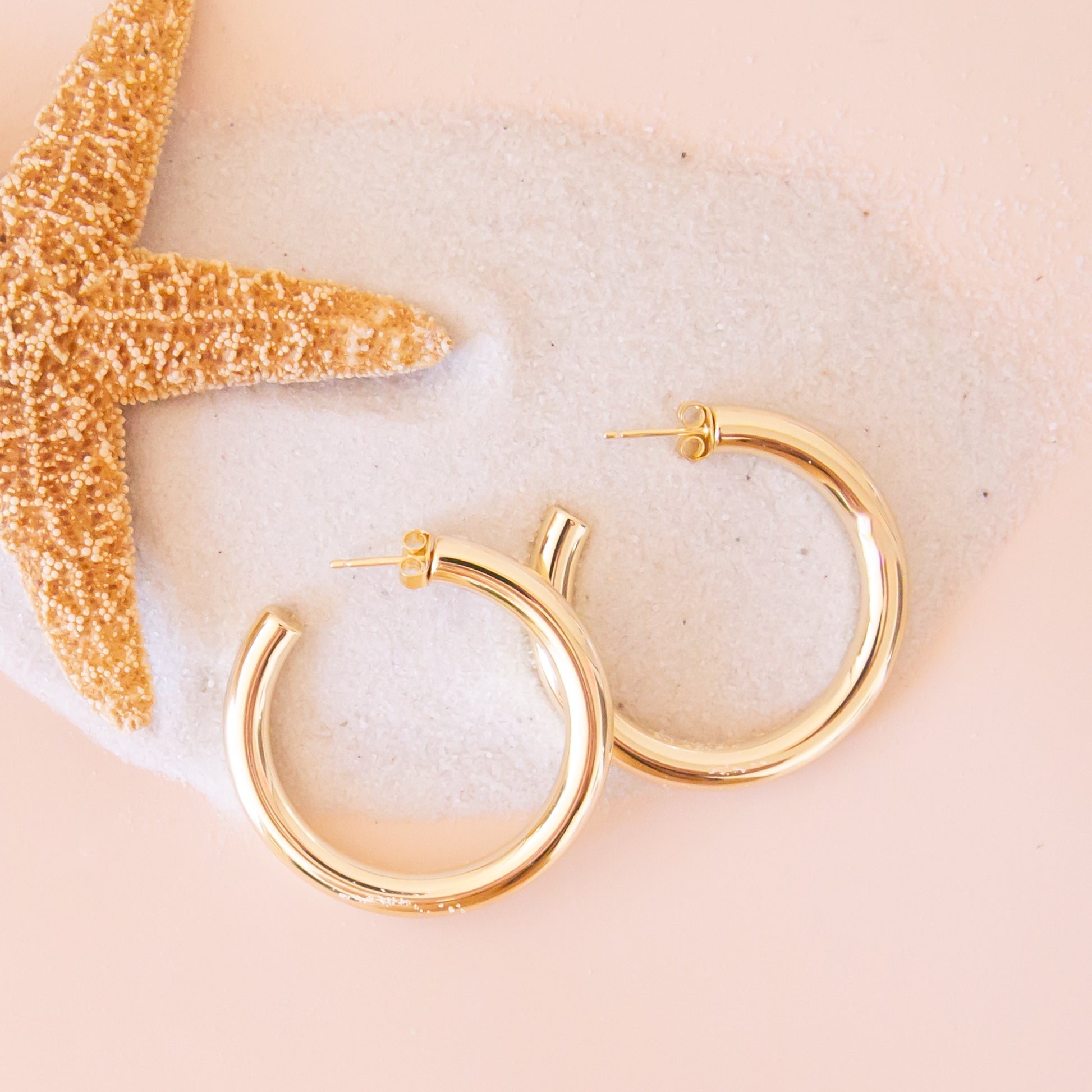 A pair of chunky gold hoop earrings with a straight post backing. 