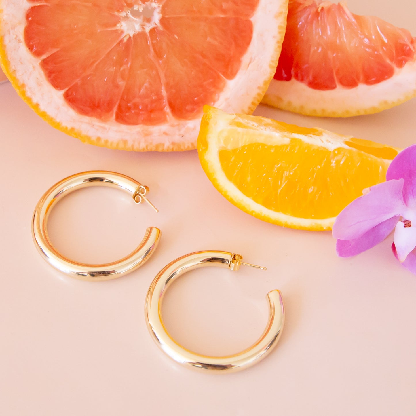 A pair of chunky gold hoop earrings with a straight post backing. 