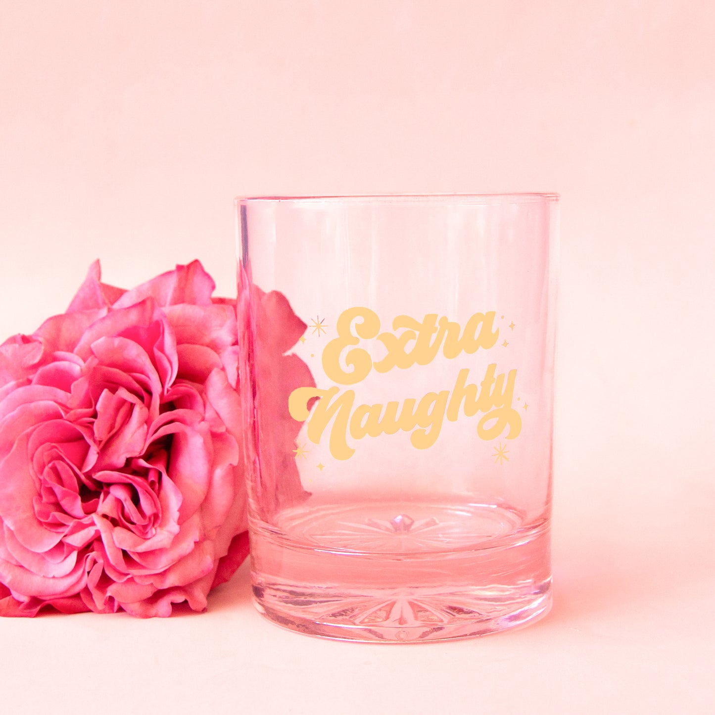 pink glass tumbler with gold script font that says "extra naughty"