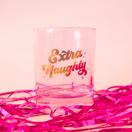 pink glass tumbler with gold script font that says "extra naughty"