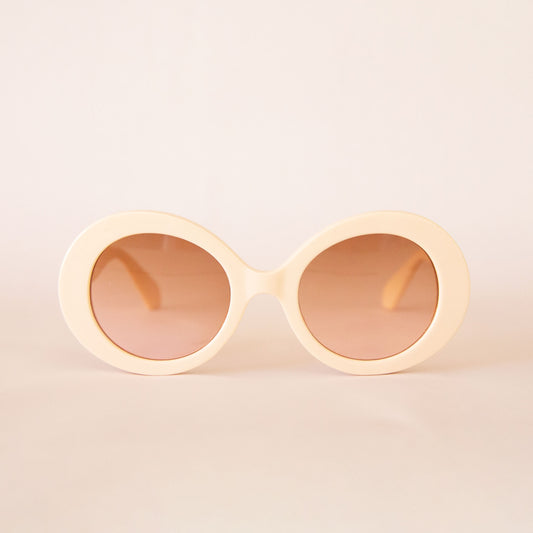 A pair of ivory round sunglasses with a cream/brown lens