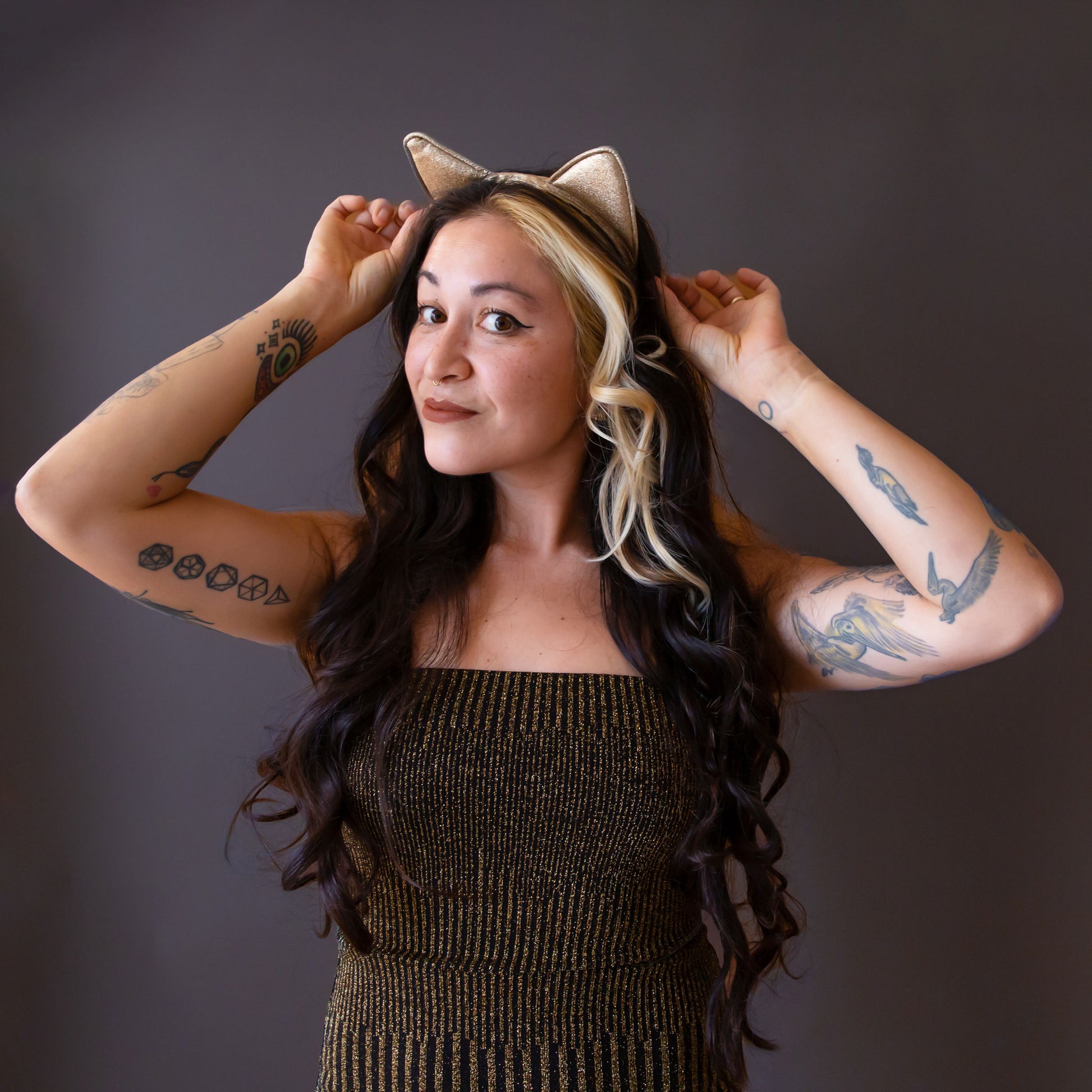 Model in leopard body suit with red hair wears a gold glitter cat ears headband.