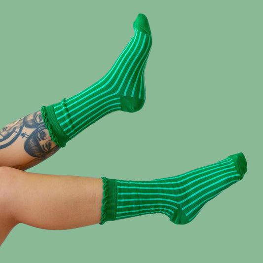 A pair of emerald green crew socks with a lighter green stripe and a ruffle edge at the top. 
