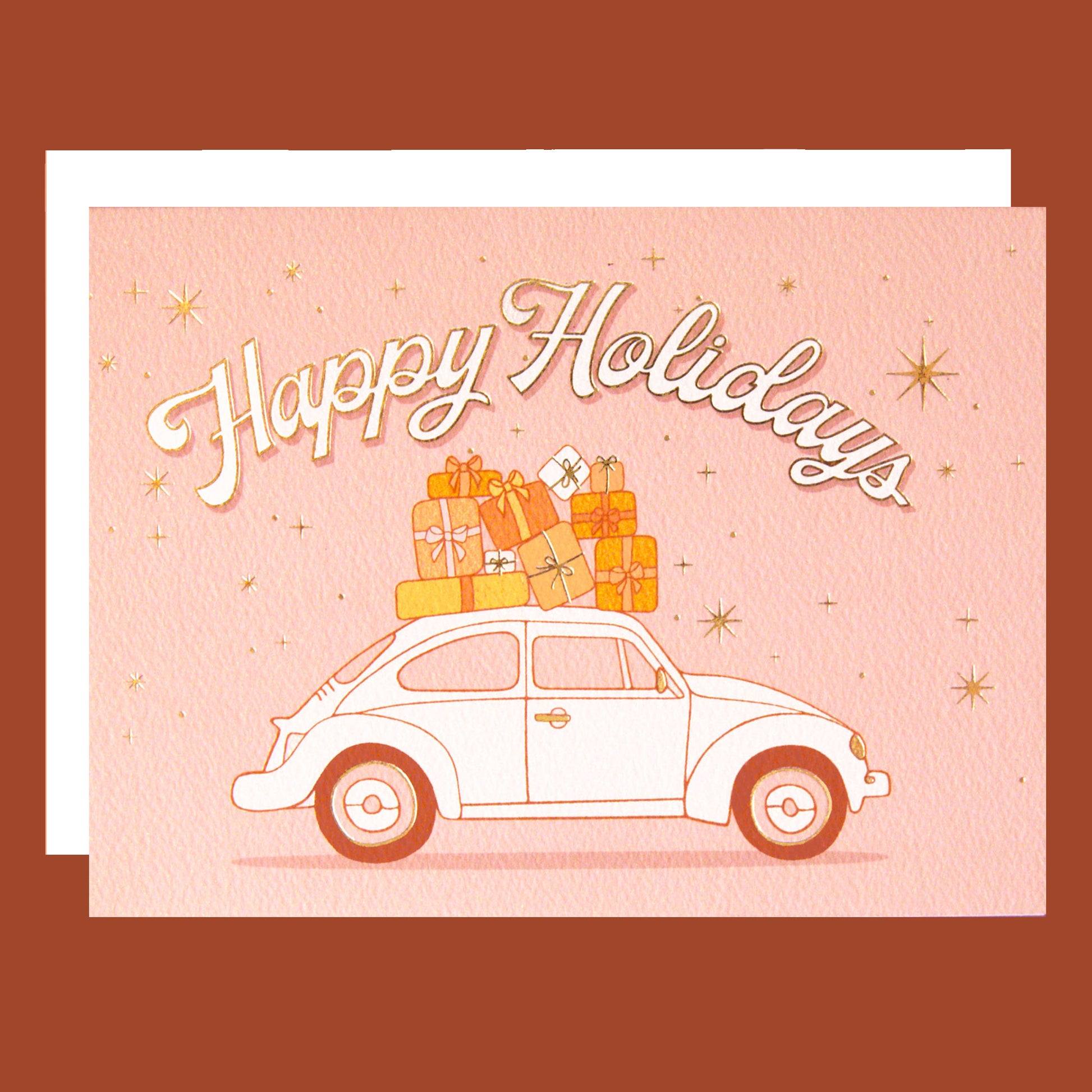 On a pink background is a card with a VW bug with gifts on top and text arched above it that reads, "Happy Holidays".