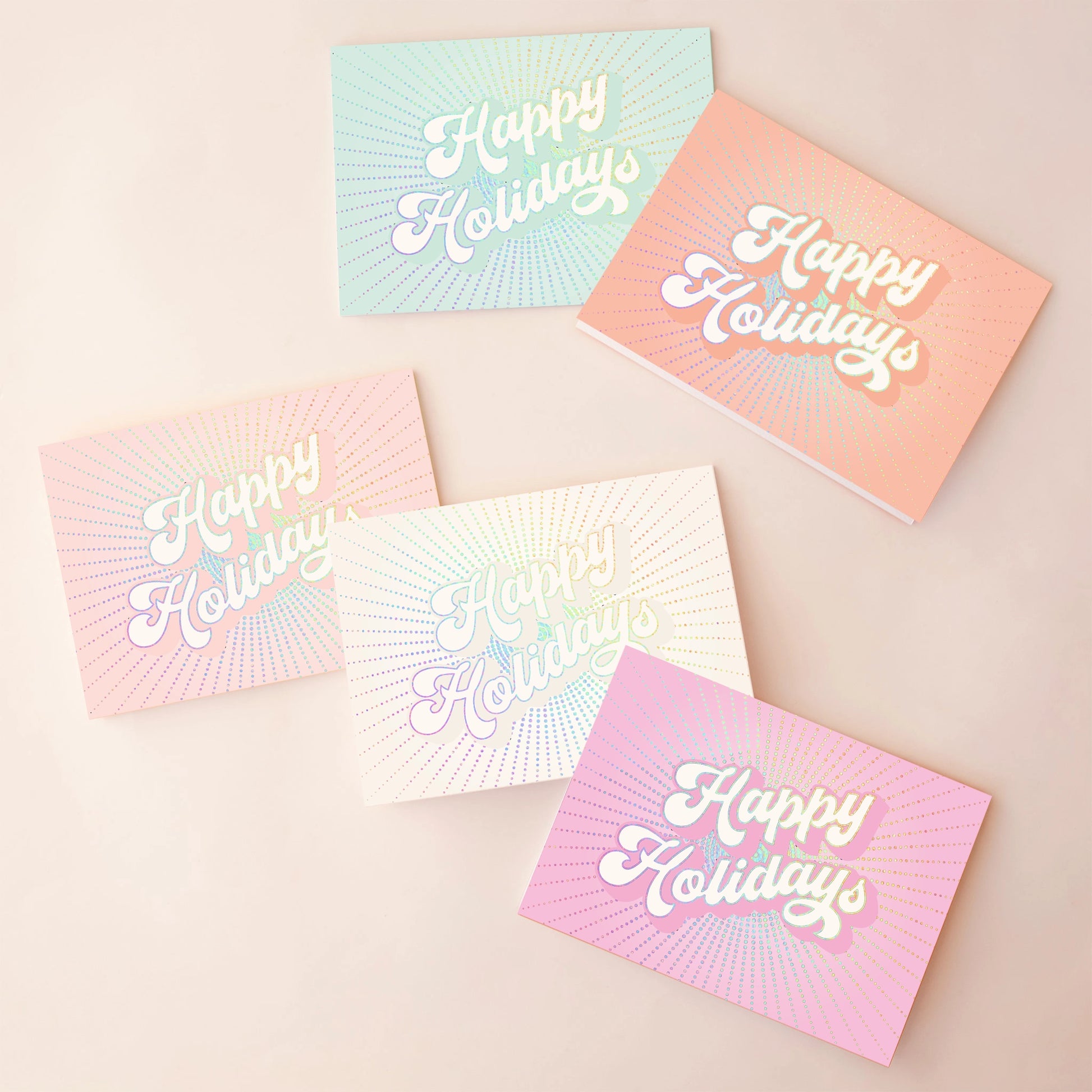 On an ivory background is a 5 pack of holiday greeting cards in shades of pink, ivory, blue, orange and hot pink. 
